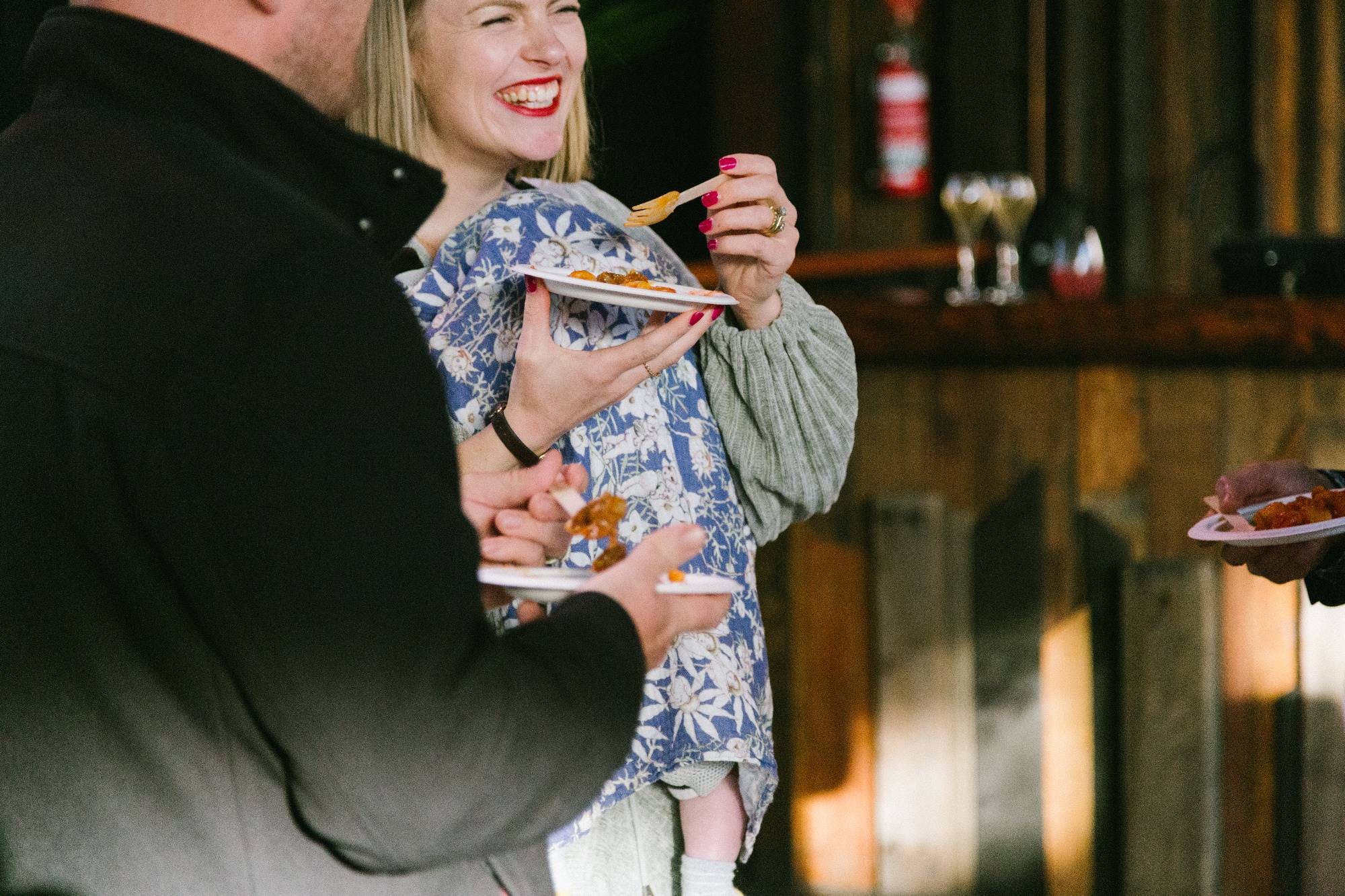 A woman smiling while holding a fork and eating gnocchi